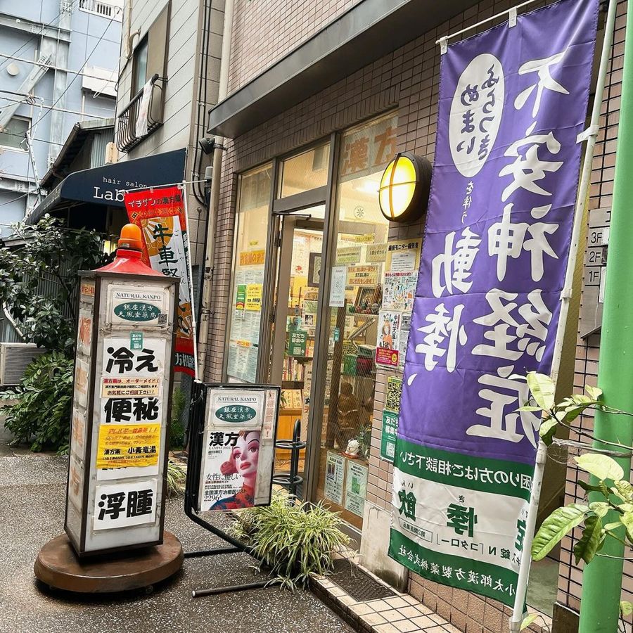 Entrance of Ginza Kampo Tenpudo Pharmacy with a purple banner and a street sign